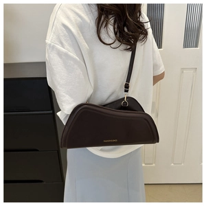 Détail d'un sac à bandoulière marron foncé asymétrique avec bandoulière et anneau en métal