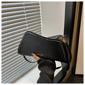 Détail du sac à bandoulière noir minimaliste avec logo doré et design incurvé unique