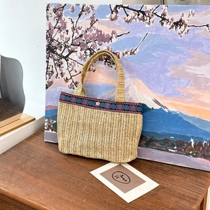 Handwoven beige clutch bag with ethnic geometric patterns and silver metal snap closure