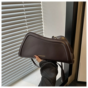Détail du sac à main en cuir chocolat montrant les coutures et le logo doré