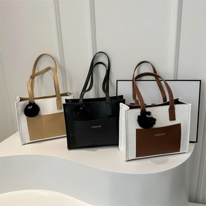 Three minimalist color-block tote bags on a sleek white pedestal with cute charms