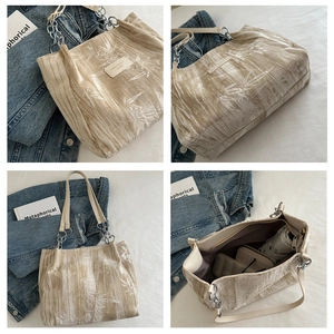 Detail of beige tote bag with bamboo leaf jacquard fabric, leather straps and metal chain