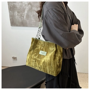 Detail of green velvet shoulder bag with bamboo leaf patterns and silver chain strap