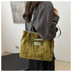 Detail view of the green velvet tote bag showing textured fabric and chain strap