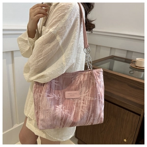 Close-up of pink tote bag with leaf texture and silver chain strap on a model