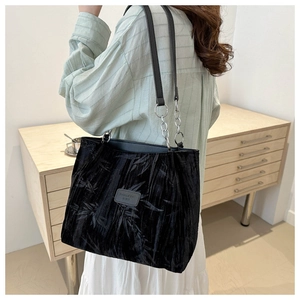 Detail of black suede tote bag featuring bamboo leaf patterns and silver metal chain strap