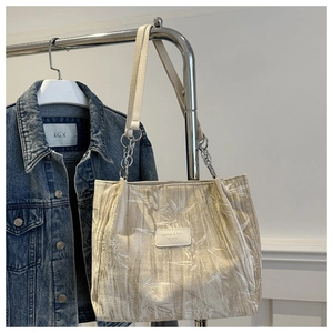 Close-up of beige floral tote bag with chain strap and leather logo patch