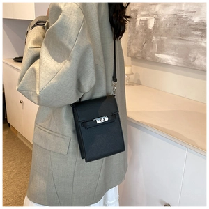 Detail of a black mini crossbody bag with a silver rotary lock and slim shoulder strap