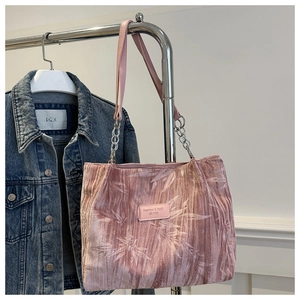 Detail of pink pleated fabric tote bag with plant patterns and silver chain strap