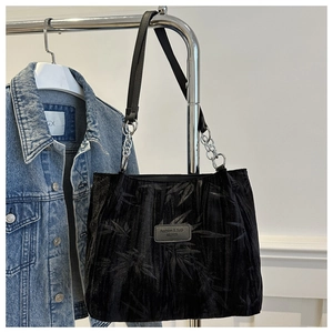 Detail of black tote bag with silver chain strap and subtle bamboo leaf pattern print
