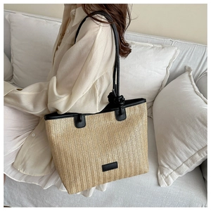 Close-up of the woven texture and black leather strap details on a large beach tote bag