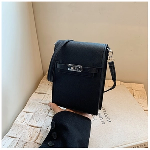 Detail of black cross-grain leather mini bag with silver clasp on a stone surface
