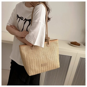 Close-up of woven straw tote bag with brown leather straps and herringbone pattern
