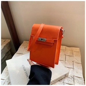 Detailed view of bright orange cross-grain leather mini crossbody bag with silver clasp