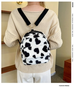 Detail of plush cow print backpack with heart spots and gold metal hardware