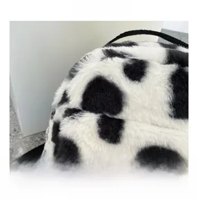 Detail view of the soft cow print plush fabric and black shoulder strap on the backpack