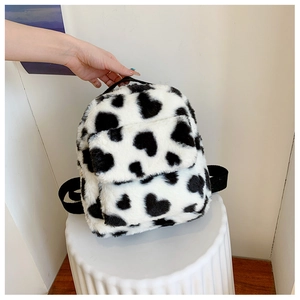 Close-up of mini plush cow print heart pattern backpack with soft faux fur texture