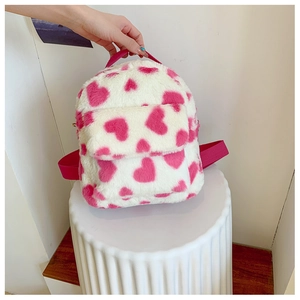 Close-up of pink heart pattern on white plush backpack with soft faux fur texture