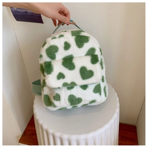 Detail of plush cow print mini backpack with green heart patterns and top handle
