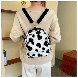 Detail of plush cow print backpack with heart spots and gold metal hardware on strap