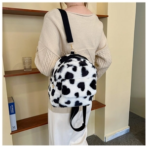 Close-up of soft cow print plush backpack with heart pattern and nylon straps