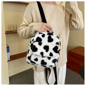 Detailed view of mini plush backpack with black and white cow print and heart patterns