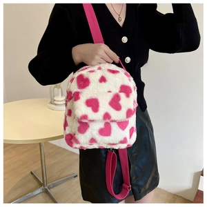Detail of plush mini backpack featuring pink heart patterns and adjustable straps