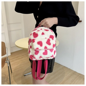 Detail of plush backpack with pink heart pattern and adjustable shoulder straps