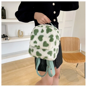 Detail of cute plush backpack with green heart pattern being held by model