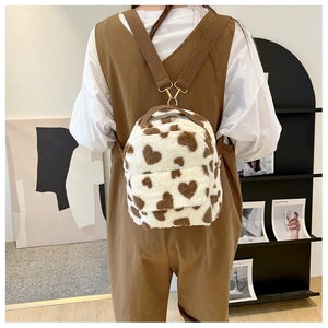 Close-up of heart pattern plush backpack with brown straps and golden metal buckles