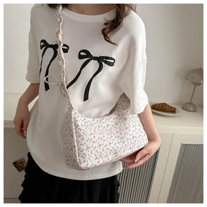 Détail du sac sous l'aisselle à fleurs avec motifs roses et bretelles à volants