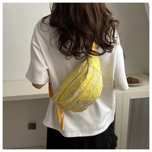 Close-up of yellow crescent shoulder bag featuring colorful quilting and rope zipper detail