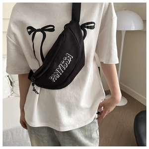 Detailopname van een zwarte crossbodytas met FANYISSA-logo op een wit casual T-shirt
