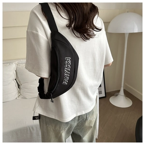 Detail van een zwarte FANYISSA crossbody borsttas gedragen door model in kamerinterieur