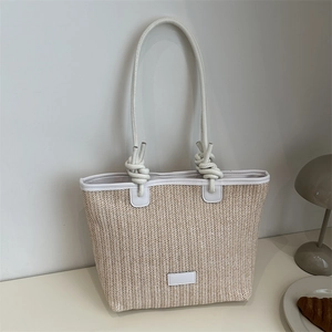 Woven straw tote bag with white leather trim and long handles for summer beach commute
