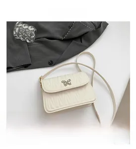 Detailed view of the white quilted shoulder bag featuring a silver butterfly clasp and strap