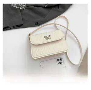 Detailed view of quilted wave texture and silver butterfly buckle on white crossbody bag