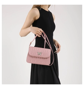 Detailed view of pink pleated handbag featuring a silver butterfly buckle on black dress