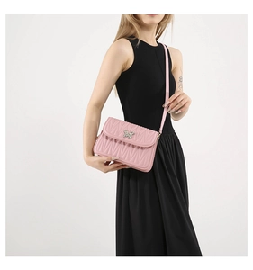 Detail of pink quilted crossbody bag featuring a sparkling butterfly metal clasp lock