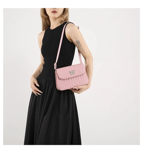 Close-up of pink quilted crossbody bag with silver butterfly buckle on a black dress