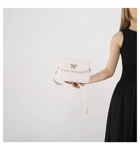 Detail of off-white quilted handbag with silver butterfly clasp and matelasse texture