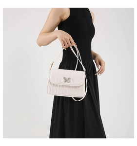 Detail of cream pleated leather bag with a metal butterfly clasp shown on a model