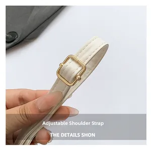Detail view of the off-white leather adjustable shoulder strap with gold buckle hardware