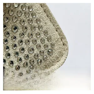 Macro shot of beige tweed fabric texture decorated with sparkling round rhinestones
