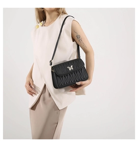 Detail view of black quilted leather shoulder bag with silver butterfly buckle