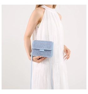 Close-up of light blue rhinestone crossbody bag on model in white lace dress