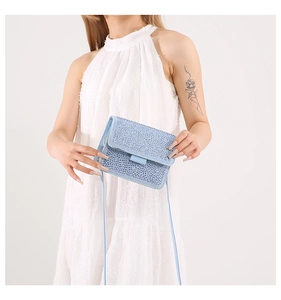 Close-up of light blue handbag featuring dense rhinestone detailing and flap closure