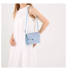 Close-up of light blue rhinestone shoulder bag on white dress for elegant evening look