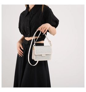 Detailed close-up of a white rhinestone shoulder bag with elegant flap design and crystals
