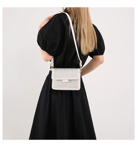 Detailed back view of a white rhinestone crossbody bag worn by a model in a black dress